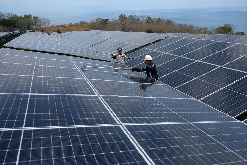 Dua petugas PLN Indonesia Power UBP Bali membersihkan panel surya pada Pembangkit Listrik Tenaga Surya (PLTS) di Pulau Nusa Penida, Klungkung, Bali, Selasa (22/10/2024). PLTS tersebut menyediakan sumber energi bersih yang ramah lingkungan dengan kapasitas